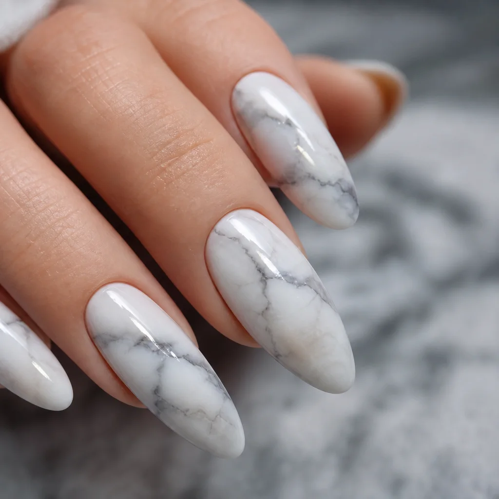 Marble nail art with white and gray veining on a glossy almond nail shape