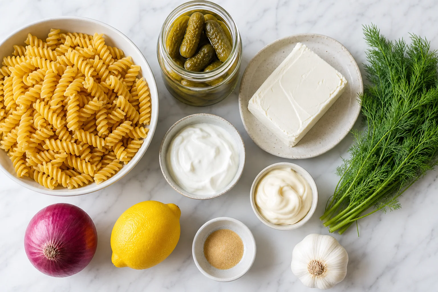 Dill pickle pasta salad ingredients including rotini pasta dill pickles cream cheese sour cream red onion and fresh dill