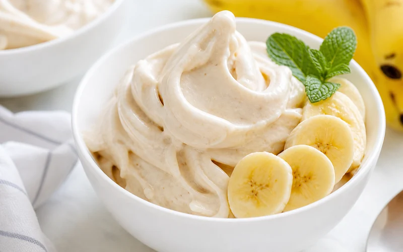 Creamy banana nice cream scooped in a bowl with fresh banana slices