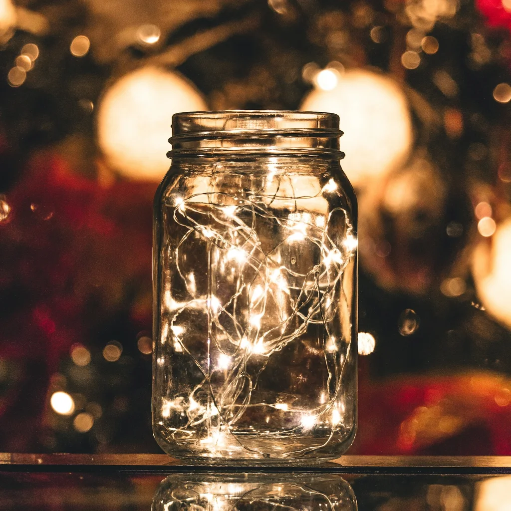 Classic mason jar lantern filled with warm fairy lights on a wooden table