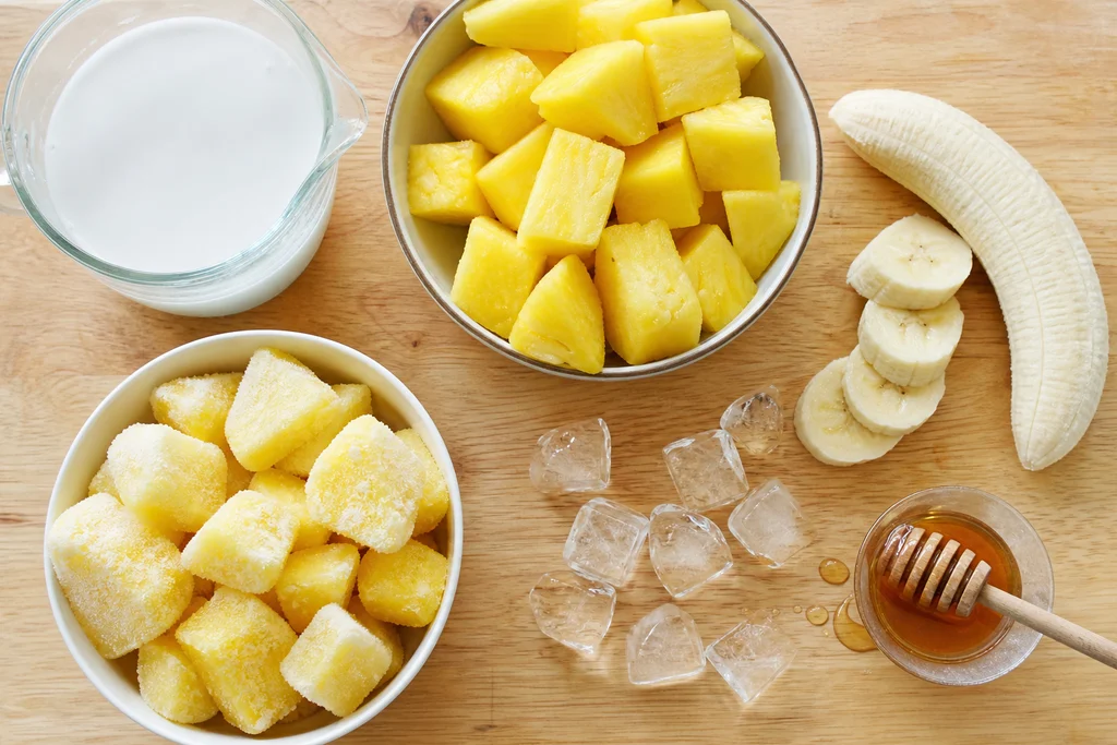 Fresh pineapple coconut milk banana and ice ingredients for piña colada smoothie