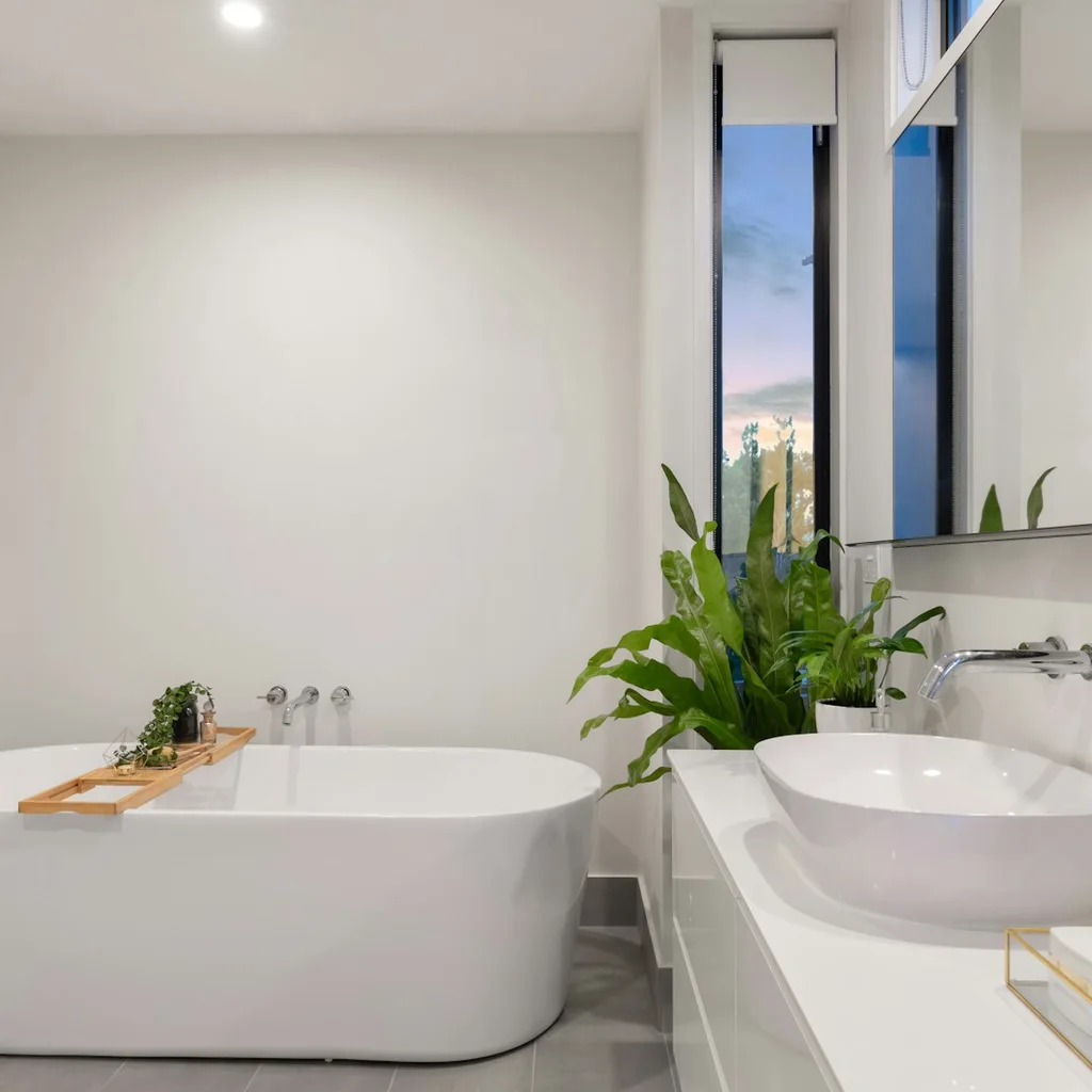 Small bathroom with light wall tiles and white fixtures that reflect natural light