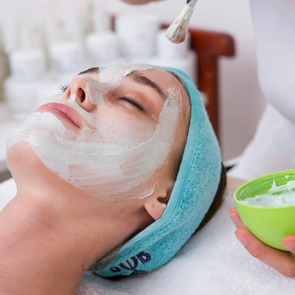 Woman applying hydrating moisturizer for a glowing complexion in soft natural light