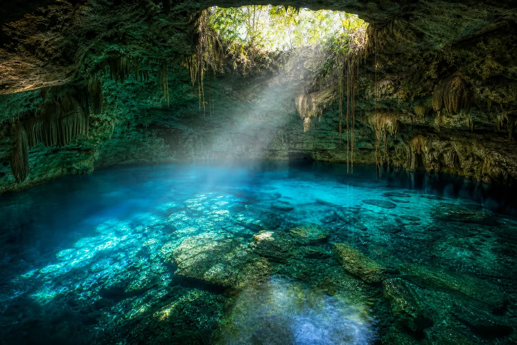 Bright blue cenote swimming hole in Riviera Maya Mexico limestone cave