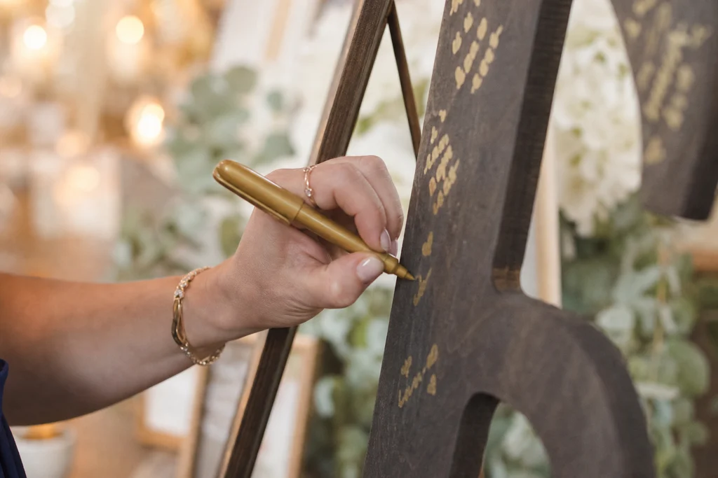 Wedding guest writing a message on large wooden initial letters