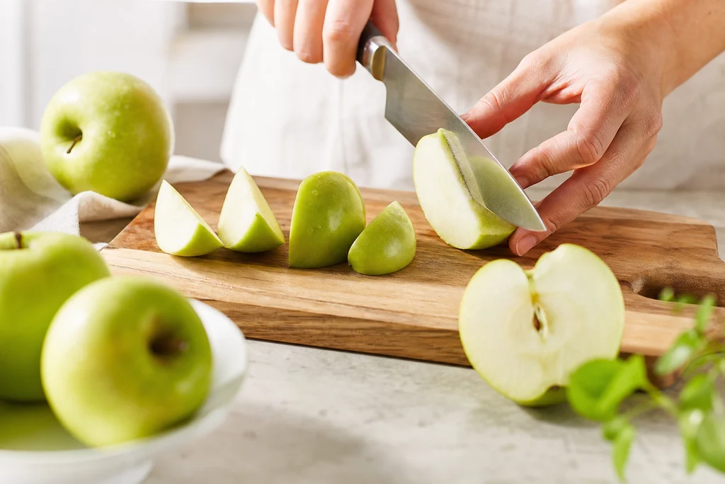 Slicing firm apples into wedges on a wooden cutting board