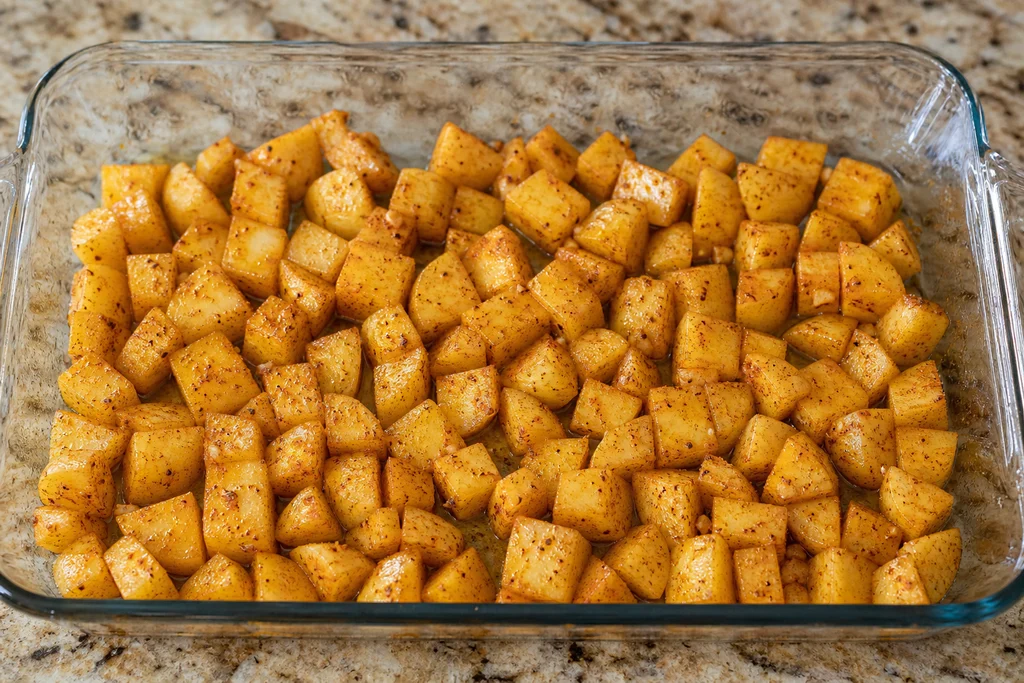 Seasoned diced potatoes in a greased baking dish for loaded potato chicken casserole