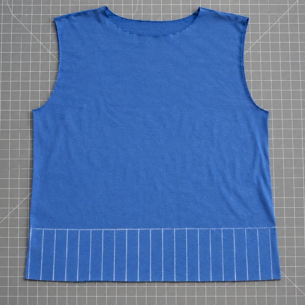 One-inch-wide by three-inch-long chalk fringe guides marked evenly across the bottom of a blue T-shirt