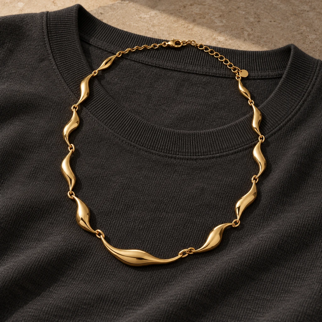 One sculptural gold necklace displayed over a plain dark top
