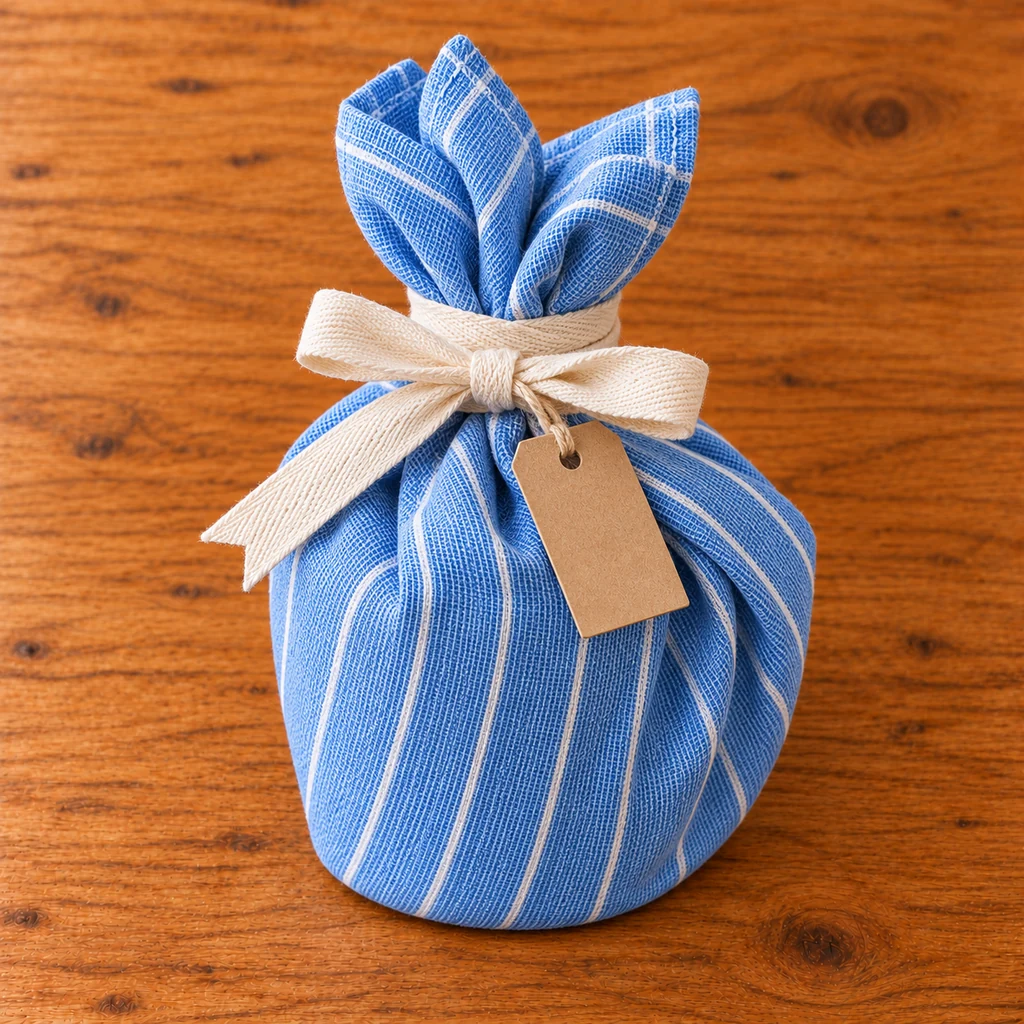 Cream cotton ribbon tied around a blue tea towel mug wrap with a kraft tag
